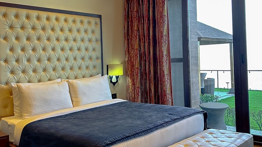 Elegant bedroom with plush bedding and mountain-view balcony at Aranya Himalayan Retreat, Mashobra