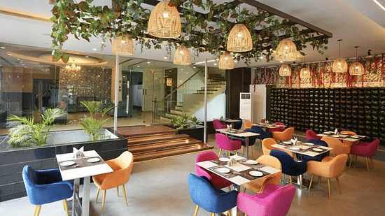 A dining area with hanging decorations, colourful chairs, and set tables, creating a lively atmosphere - VITS Gurugram
