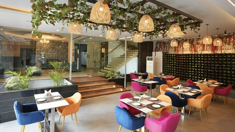 A dining area with hanging decorations, colourful chairs, and set tables, creating a lively atmosphere - VITS Gurugram