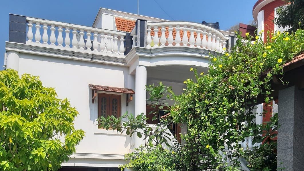 Facade of  Villa Serenity Le Sejour Pondicherry with a swimming pool in front and plants on the side.