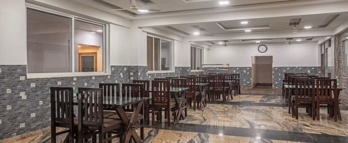 Indoor dining area with polished flooring and neatly arranged wooden tables and chairs at Siri Ambari Resorts and Spa.
