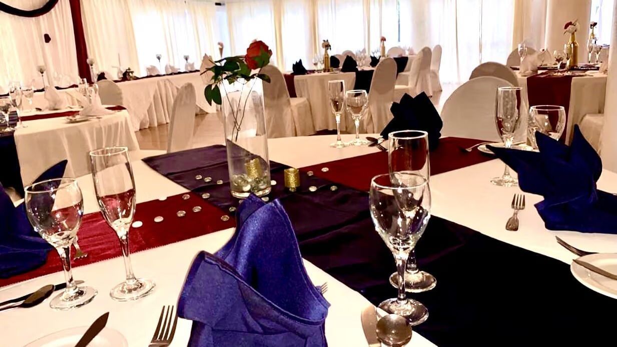 A formal dining table is set with blue and red napkins, glasses, and place settings | Luxor | Altamont Court, Jamaica