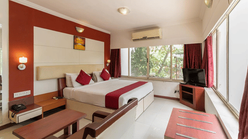 a double bed with side tables and lamps above the bed inside one of the rooms - VITS Presidency Daman