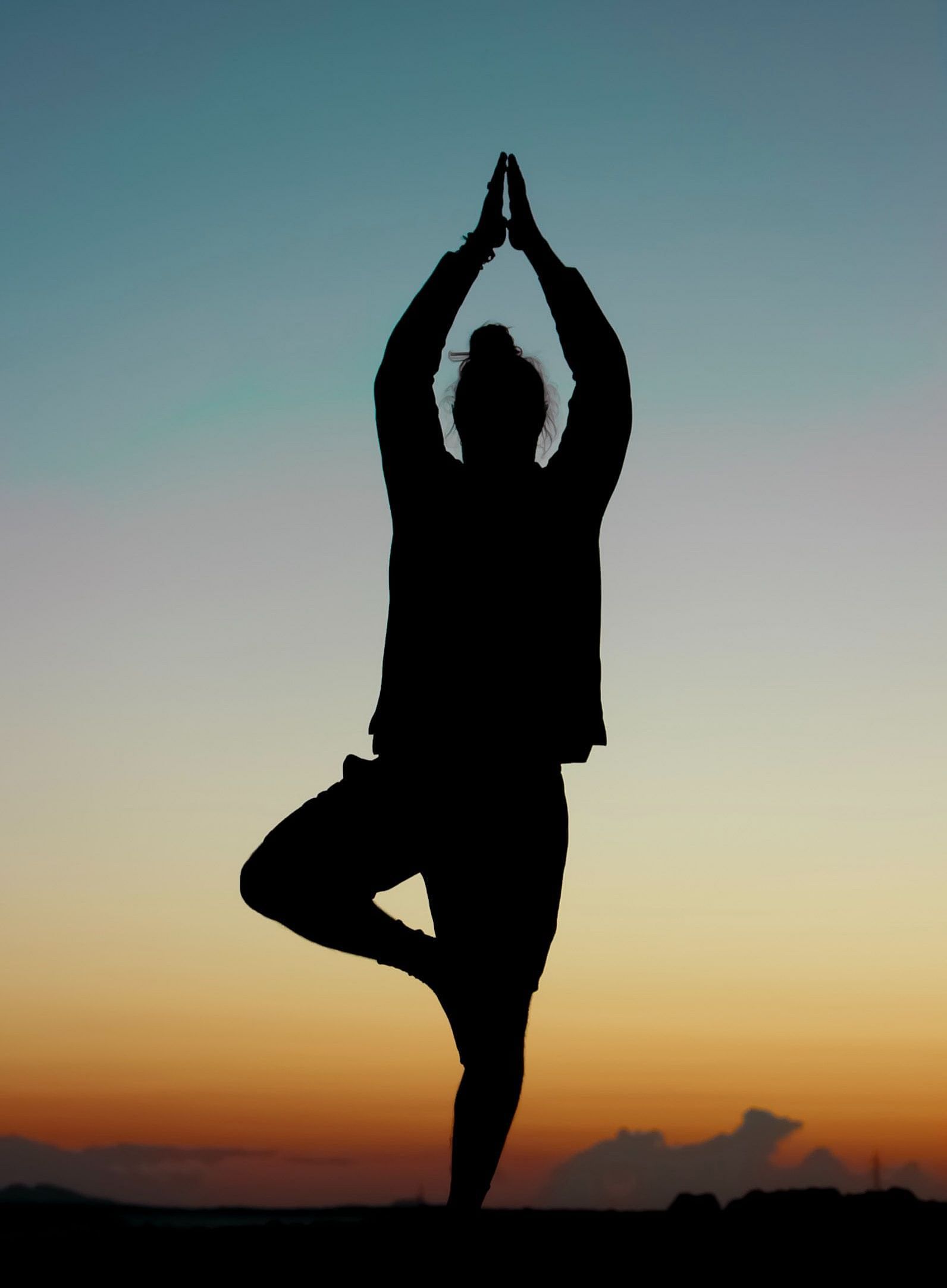silhouette of a person doing yoga with the evening sky in the backgrourd