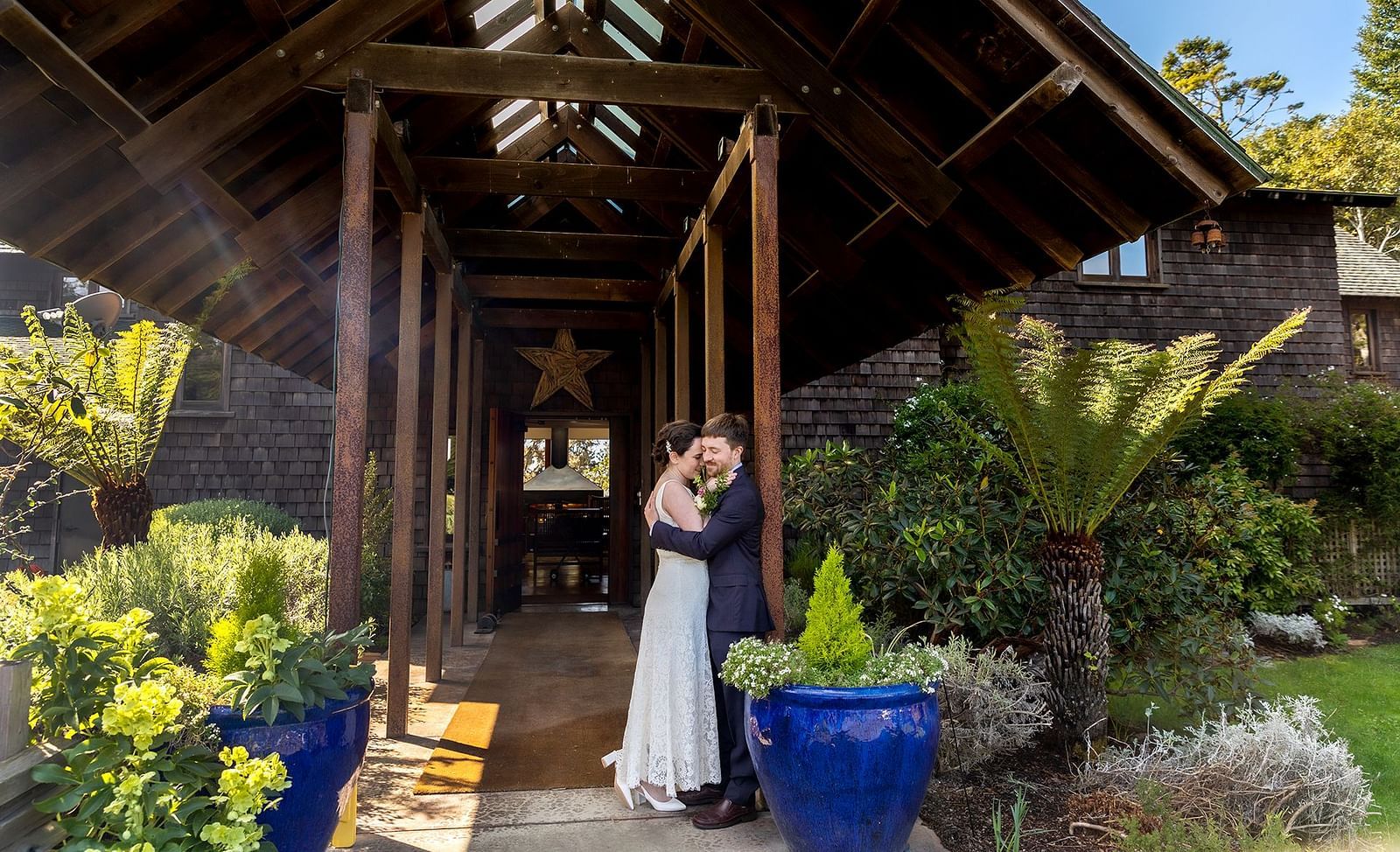 A rustic cottage framing a newlywed couple embracing each other