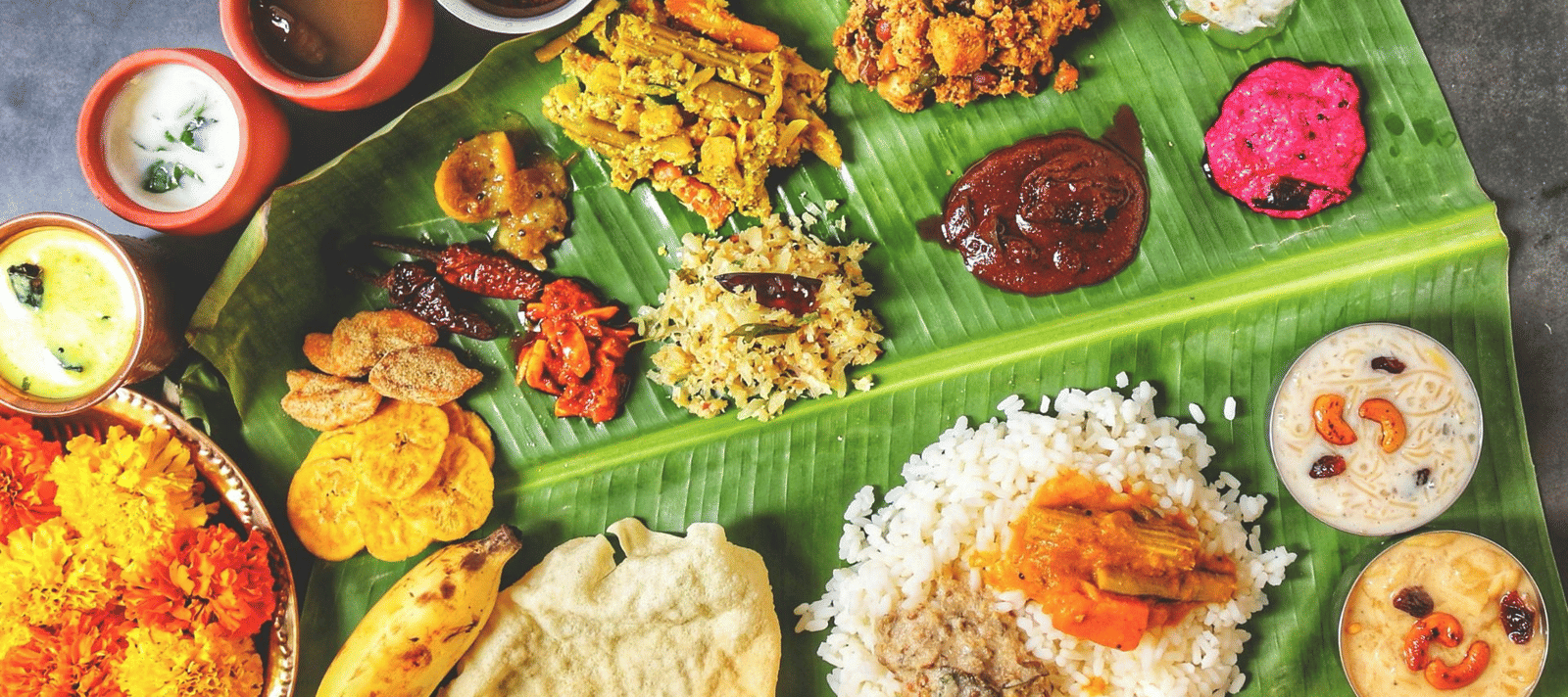 Traditional South Indian meal served on a banana leaf with rice, curries, pickles, fried snacks, and desserts.