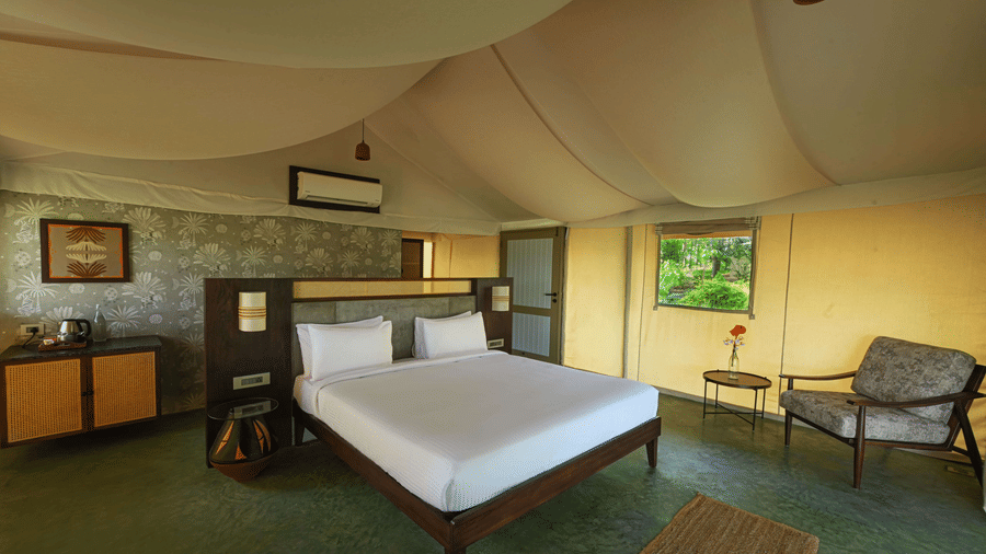 Well-furnished bedroom at Fireflies Resort Kabini featuring plush bedding, wooden furniture, and cozy interior with modern amenities.
