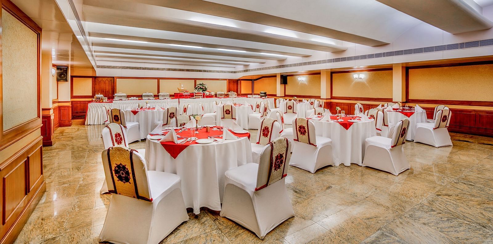A spacious banquet hall with white-clothed tables and comfortable seating, ready for an event. - Tara, Comfort Hotel in Hyderabad - Ramoji Film City.