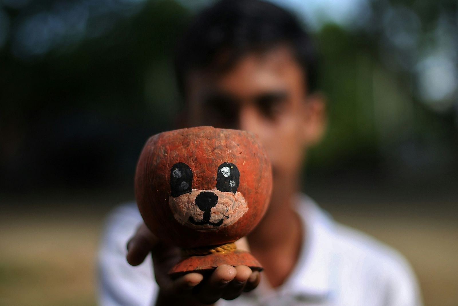 A person holding a toy made out of coconut shell with the background blurred.