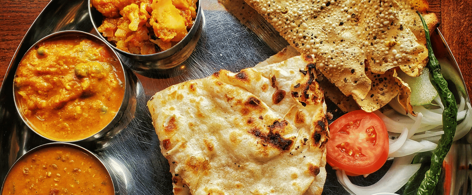 A neatly arranged plate with several Indian delicacies served.