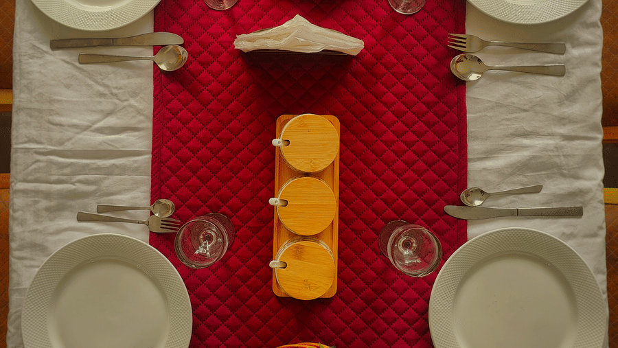 A top-down view of a rectangular dining table perfectly set for four people with fruit and salad at Indus Serenity Retreat.
