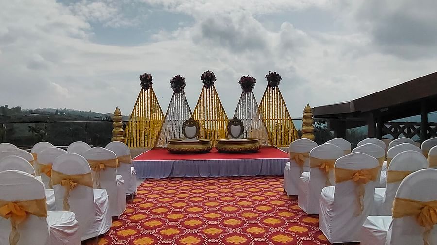 A decorated area featuring yellow and white fabric pieces, chairs, and a stage decorated with flowers and two seats meant for the bride and groom for their pre wedding rituals - The Grand Legacy Resort & Spa