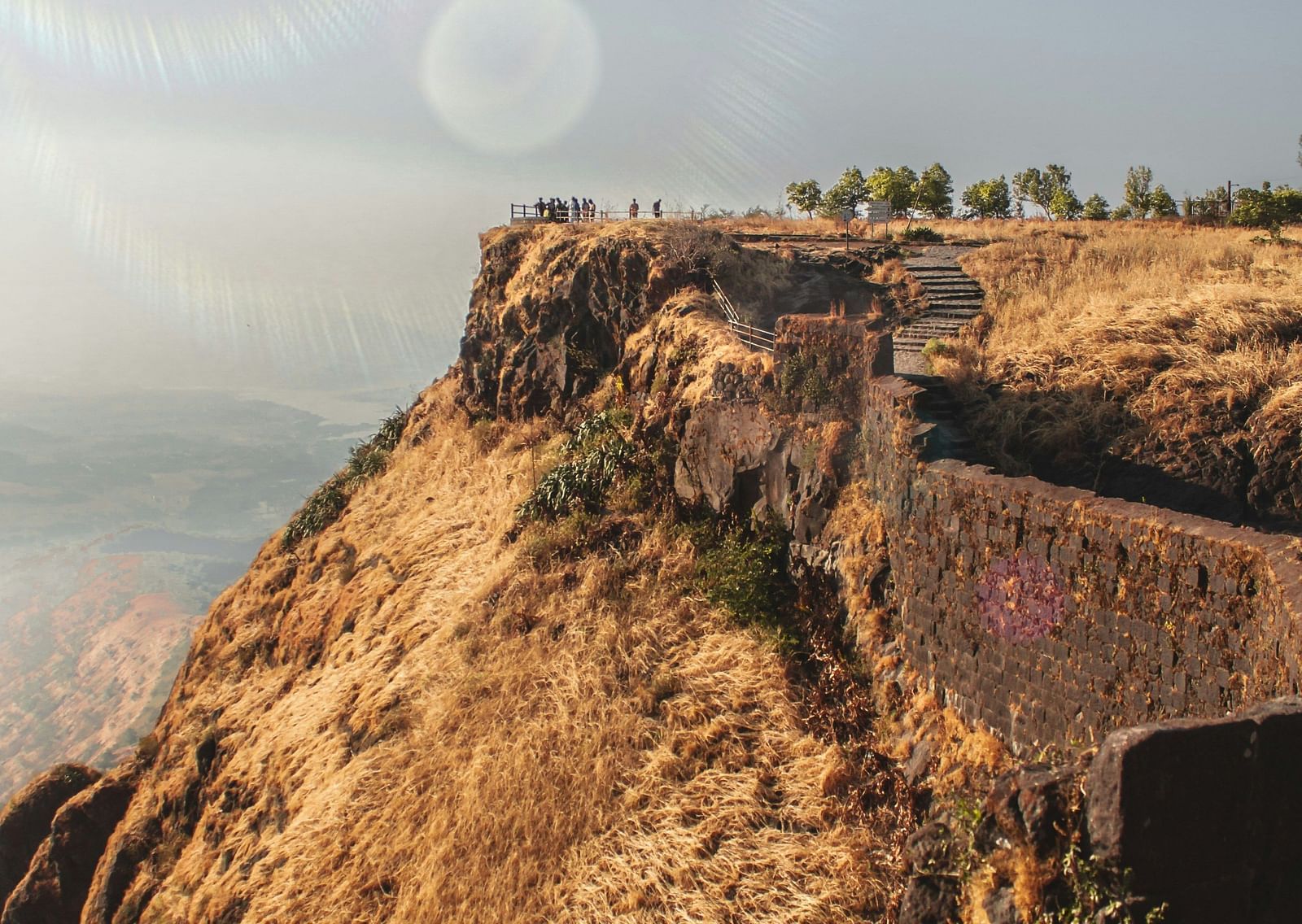 An overview of the Sinhagad Fort that is perched on a hill with stairs in view.