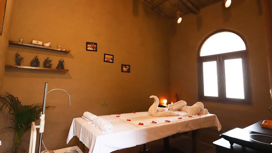 Themis Medival Wellness Centre displaying a massage table and rustic interior at Themis Mudhouse - A Nature's Retreat Resort & Wellness, oen of the best ayurvedic spa resorts near delhi