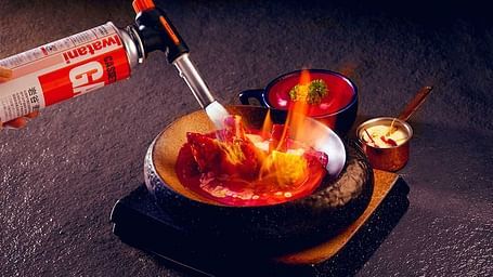 Dessert served with a syringe for flavour infusion, presented with a flaming effect.