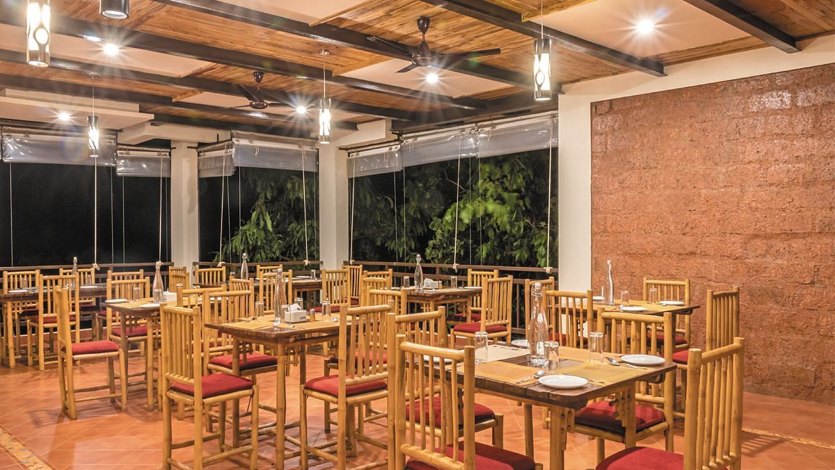 The spacious indoor dining area at Forest Escapes Koyna offers ample seating under bright lighting.