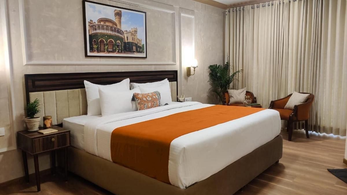 A well-lit Luxury King Room at Nalapad Hotel Bangalore International with a neatly made bed.