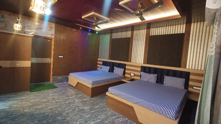 2 double beds are sitting parallel to each other inside a spacious room at Khairi Resorts.