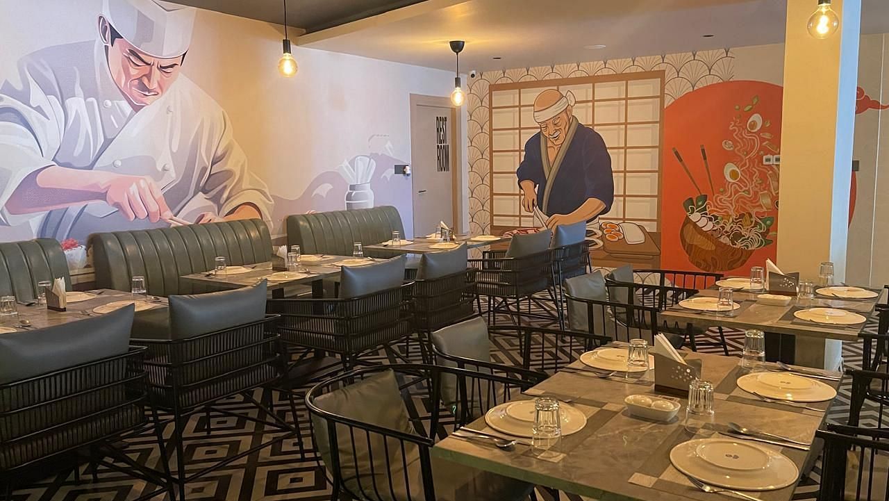 Restaurant seating area featuring artistic wall designs and neatly arranged tables at Hotel Kyzen HiTech City – Your Zenly Stay