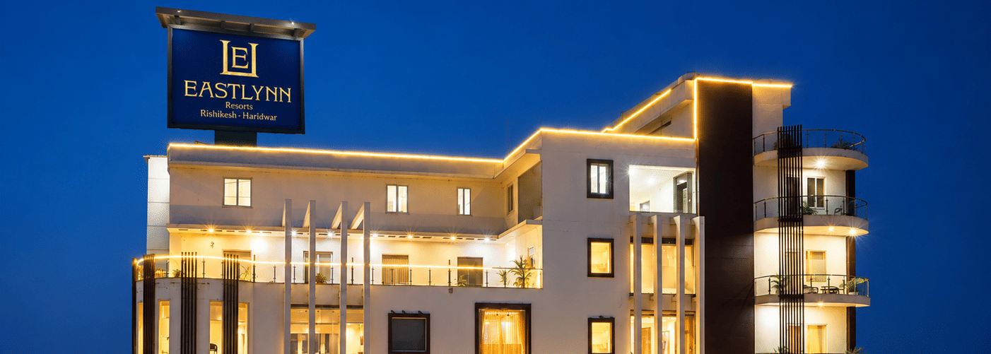 Multi storey hotel exterior lit up against the night sky at Eastlynn Resort, Rishikesh.