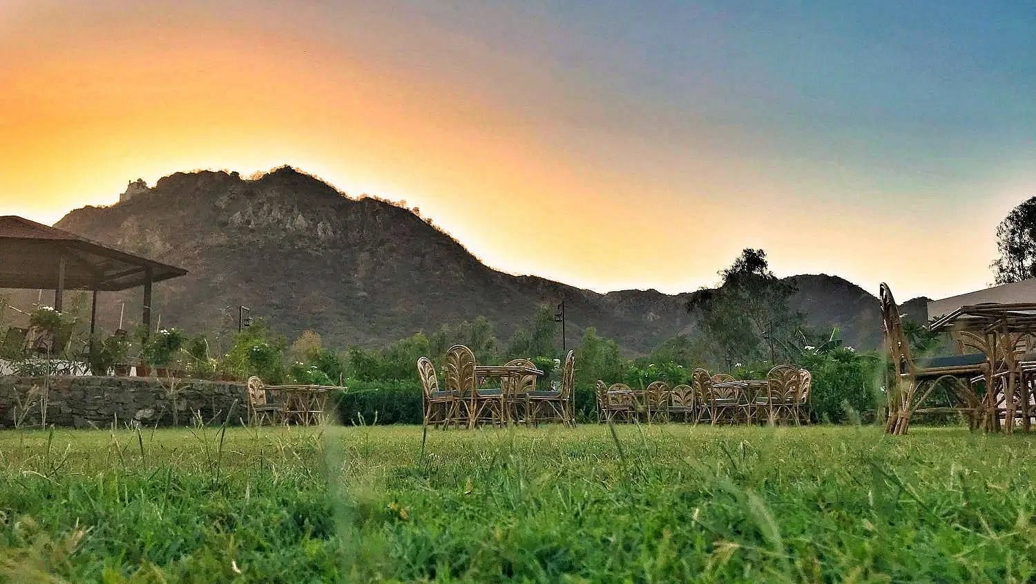 Field with hills under a bright, colourful sunset sky.
