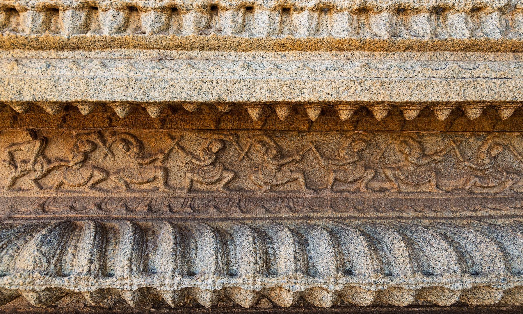 Detailed stone carving of dancing figures on temple wall.