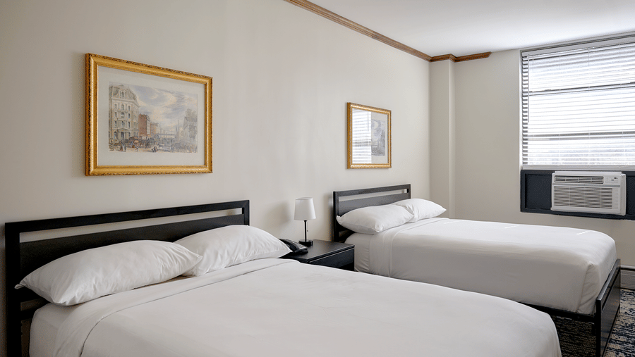 Night Hotel Broadway guest room featuring two double beds, framed artwork, and window.