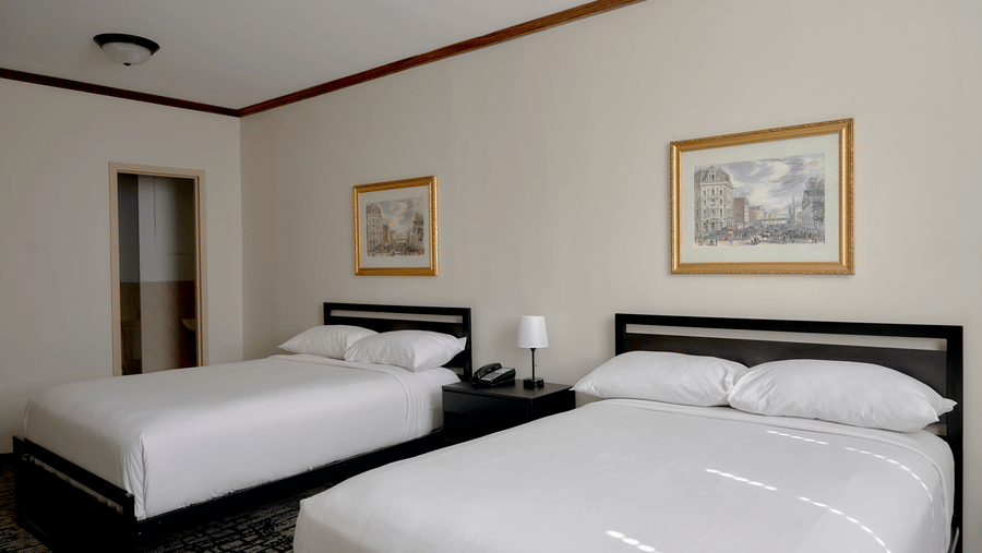 Spacious room at Night Hotel Broadway with two double beds, wall art, and bedside tables.