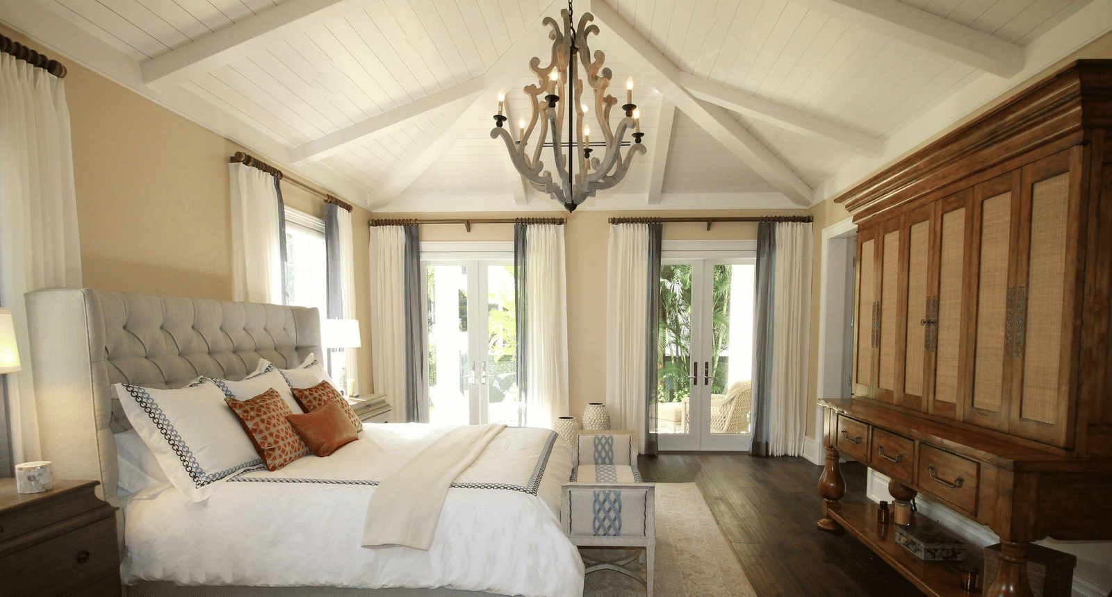 Side view image of the bed with a chandelier hanging over the double bed.