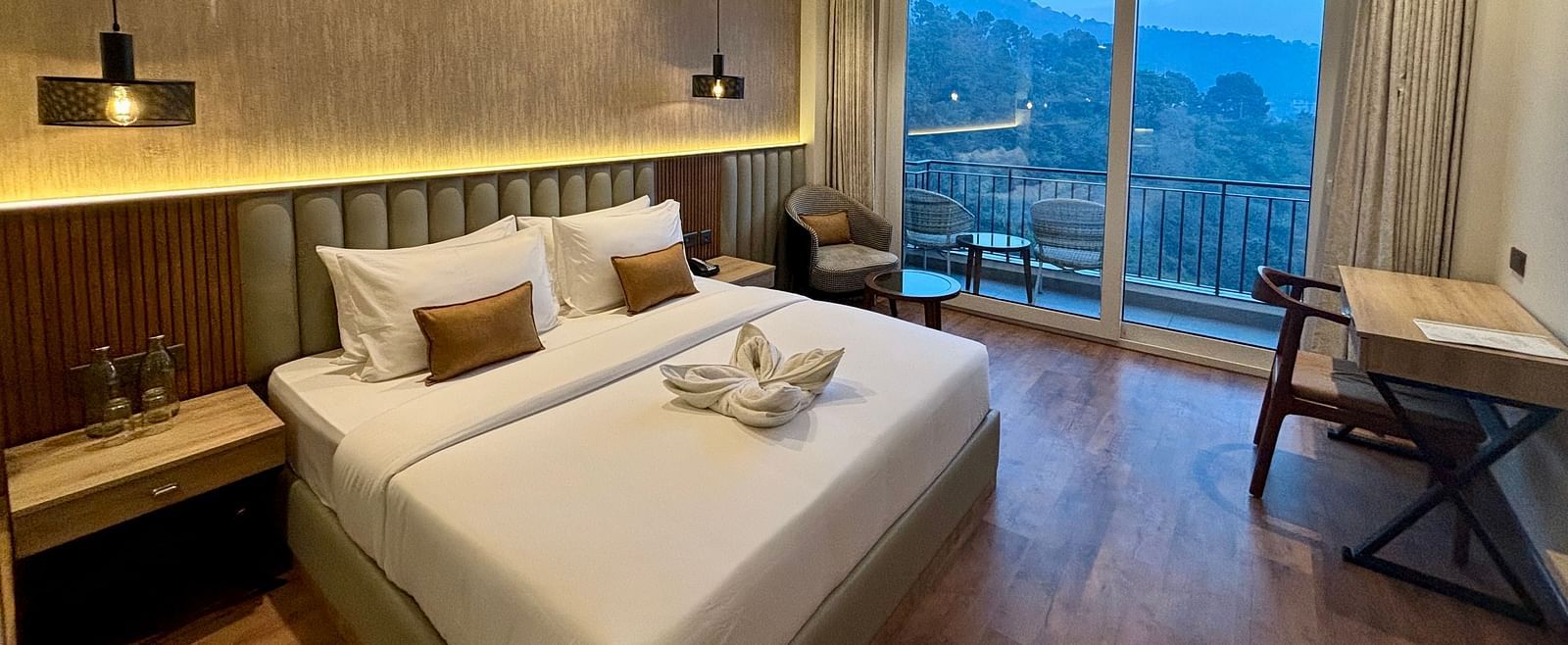 Cosy double bedroom with wooden flooring, ceiling fan, and balcony offering scenic views – ARNISA Boutique Hotel