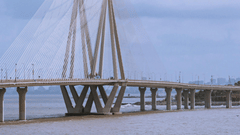 A cable-stayed sea bridge with multiple support towers and boats floating in the water below.