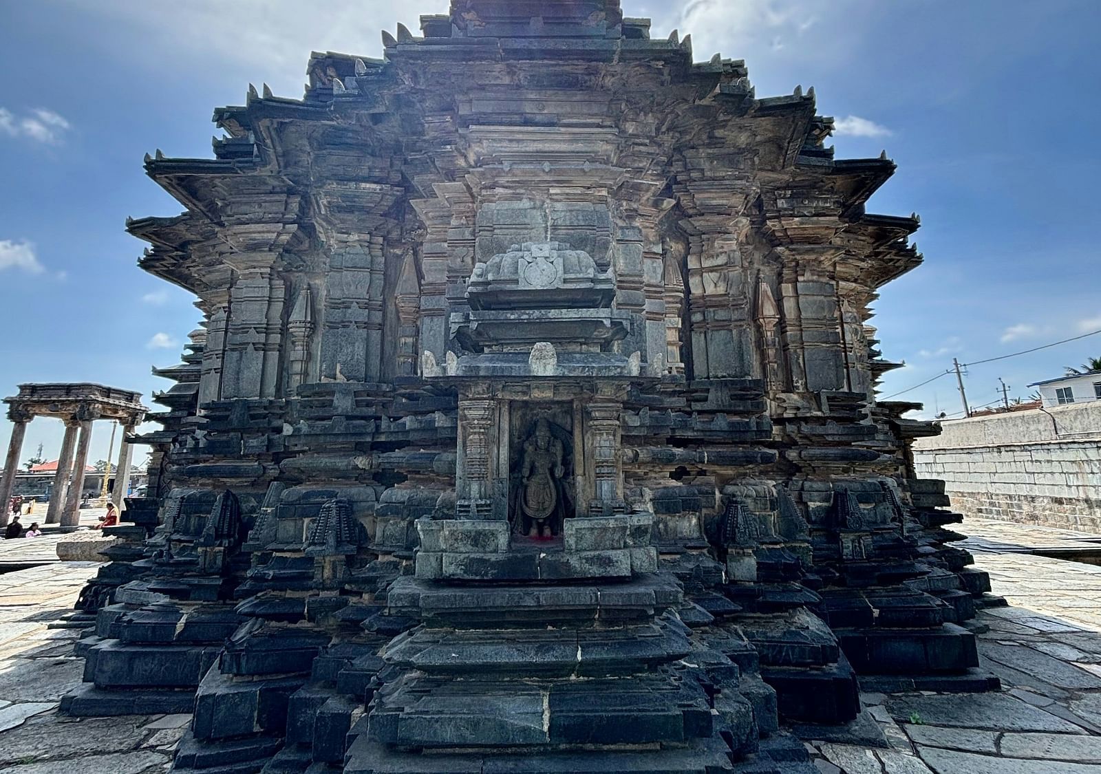 Exterior photograph of a temple with a circular design, under a bright sky.