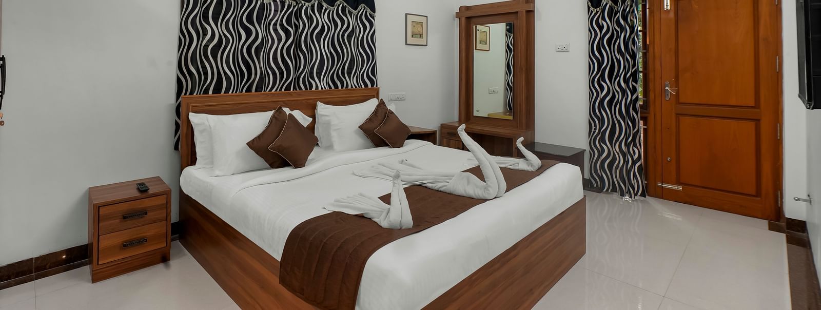 Diagonal view of a room showing a large bed with towel decorations at WOW Bungalow, Yercaud. 