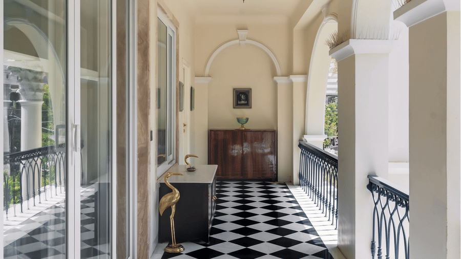 Bright hallway at Dileep Kothi, Jaipur with arched windows, checkered flooring, and heritage-style decor.