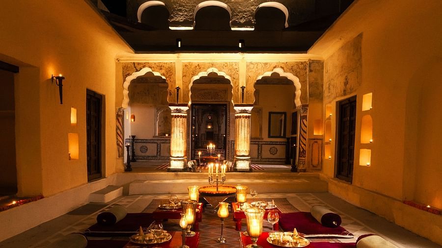 A softly lit courtyard at Fort Barli, with arched doorways and floor seating, creates a magical evening ambience.