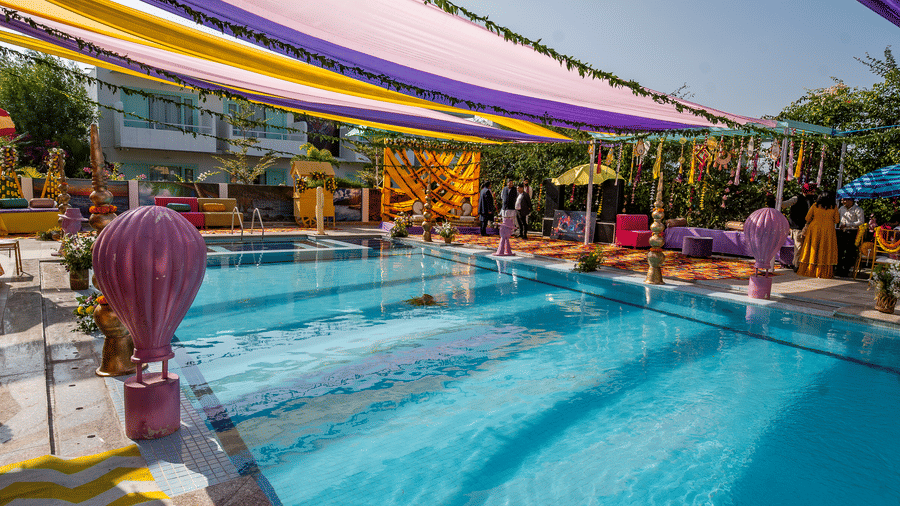 A festive poolside area with colourful purple and yellow fabric draping overhead and reflective water, highlighting a daytime event at Vedikant Resorts The Mallard Corbett.
