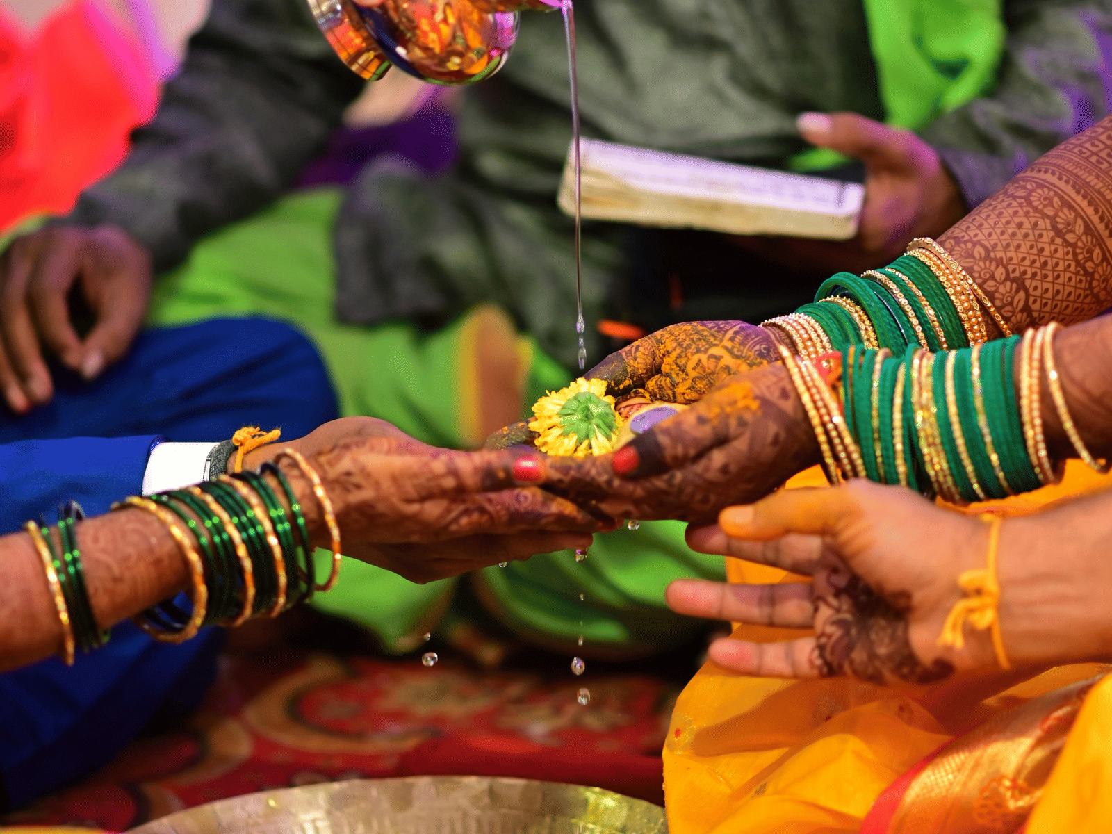 Traditional mehndi being drawn on a woman’s hand as part of vibrant Indian wedding rituals.