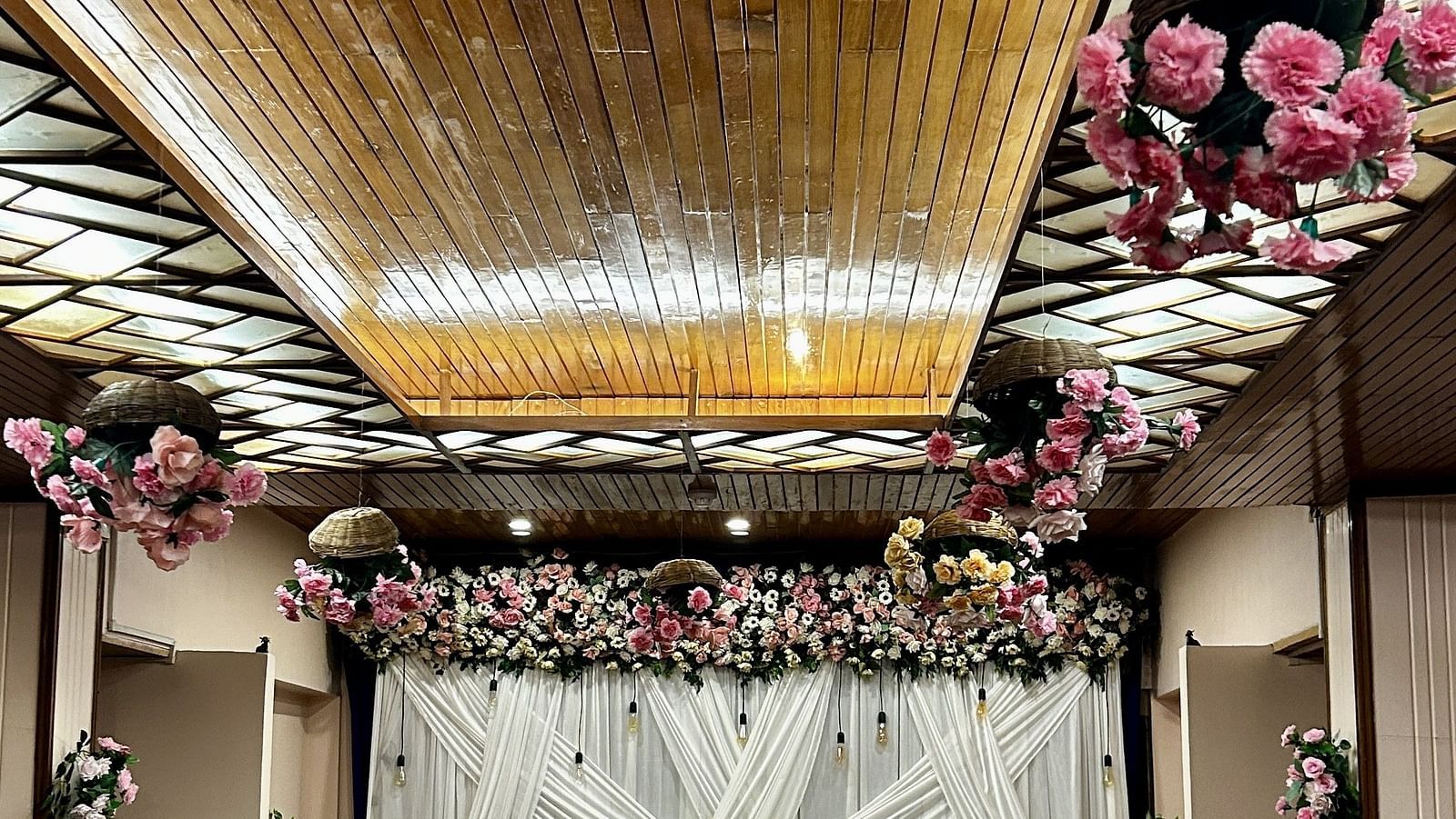 Floral ceiling decor with backdrop setup for wedding ceremony at Cedar Inn, Darjeeling, in an indoor event space.