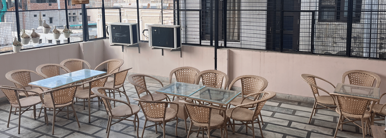 Full view of the rooftop restaurant at Perfectstayz Value Dhruv Nanda, Haridwar, with warm lights hanging from the tin ceiling along with a beautiful mountains in the background.