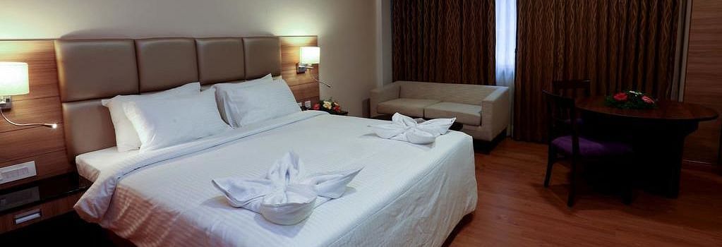 Side view of room with bed, sofa and table with chair at Fressotel Seetharam, Coimbatore