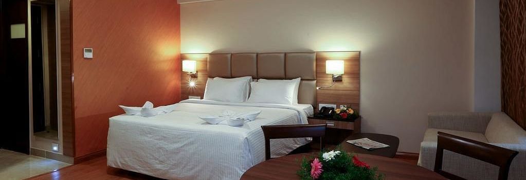 Room with bed and a table with flowers on top at Fressotel Seetharam, Coimbatore
