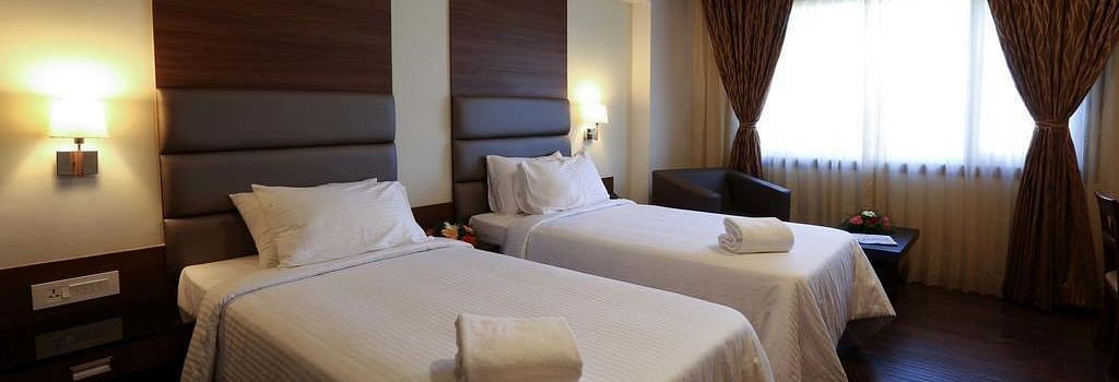 Room wtih twin beds and lamps on both sides on the bed at Fressotel Seetharam, Coimbatore