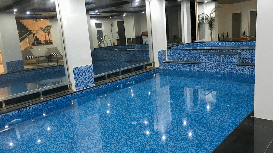 An expansive swimming pool divided by a partition and two pillars at DLS Hotels On The Ganges.
