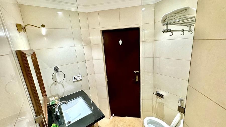 A bathroom at Luxury King Room in Nalapad Hotel Bangalore International, featuring a toilet, tiles, and a door.