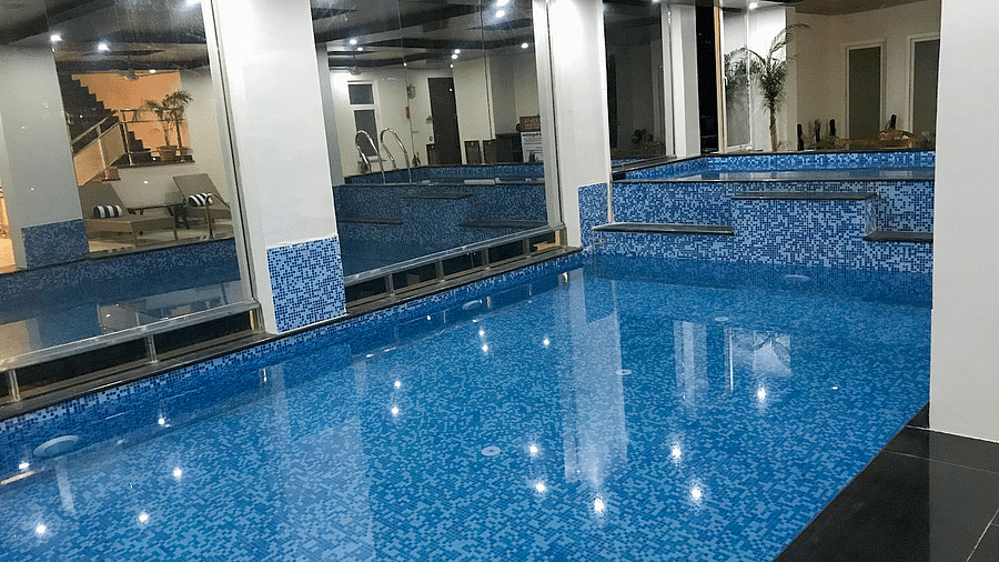 An expansive swimming pool divided by a partition and two pillars at Regenta Inn DLS.