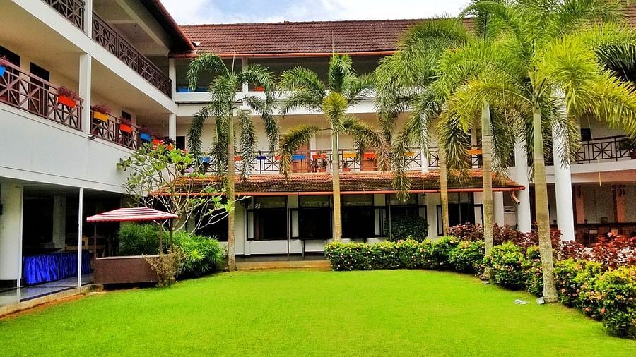 Lush green lawn with white building surrounding it - Rhythm Kumarakom