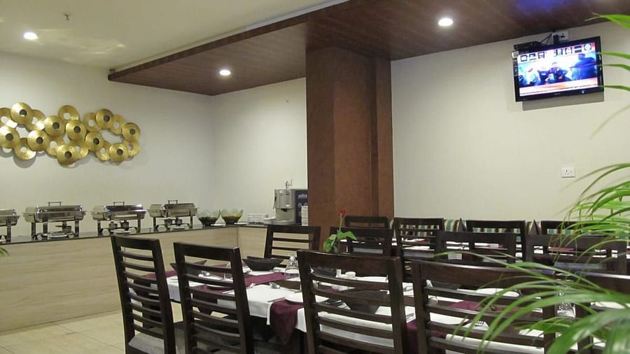 A spacious dining area with a buffet setup, wooden furnishings and a television mounted on the wall - TGI Apple Inn, Jaipur 
