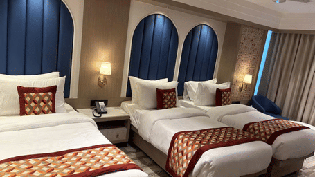 A room at Melorin with a twin beds, spreads, pillows, a mirror, and windows.