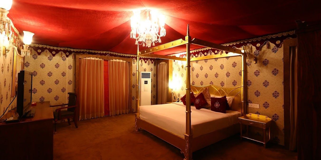 Image of a room with a bed and a chandelier hanging from the ceiling at Rajasthali Resort & Spa Jaipur. 