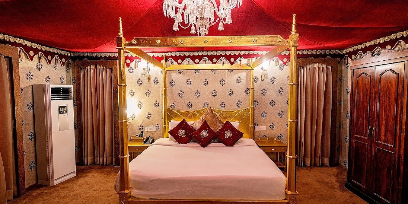 Image of Presidential Suite with a bed and chandelier above the bed at Rajasthali Resort & Spa Jaipur.